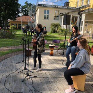 Tre personer spelar och sjunger utomhus