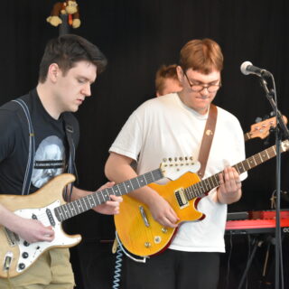 Två personer spelar gitarr i ett band