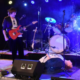 Person ligger ner framför person som spelar gitarr
